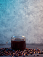 Glass espresso coffee cup stands on roasted coffee beans, creative color background copy space