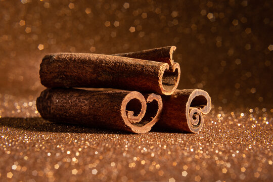 3 cascas de canela com fundo dourado com brilhos.