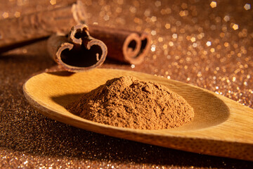 Colher de madeira com pó de canela e 3 cascas de canela.