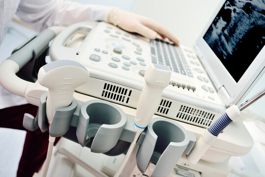 doctor's hands in medical gloves close-up against the background of a modern ultrasound machine in a diagnostic clinic.