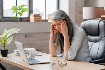 Tired sad mature business woman having headache in office