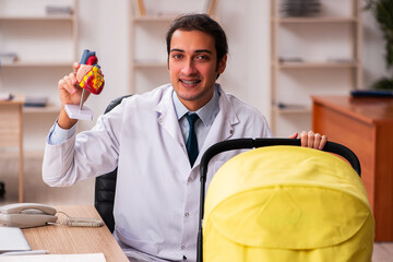 Young male doctor looking after new born in the clinic