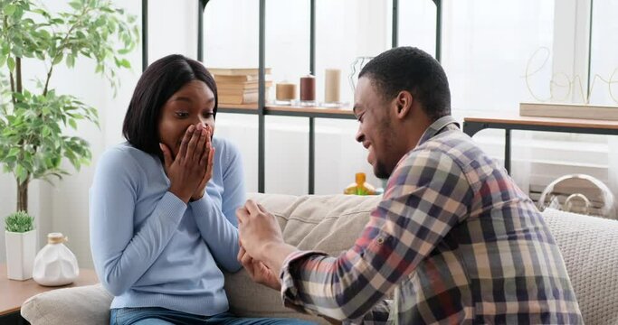 Loving man proposing woman with a ring at home