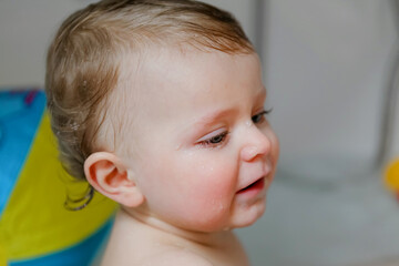 Cute adorable baby child taking bath in bathtub at home. Happy healthy boy or girl playing, splashing and having fun during bathtime. Hygiene and cleaning concept for babies.