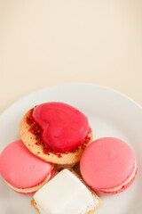 Assorted pink and white mousse cakes and macaroons on a white plate with a light background