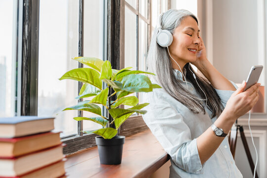 Relaxed Middle-aged Woman Listening To The Music On Phone At Home