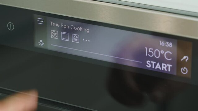 Man cook sets temperature for baking in oven. Cooking program. Oven electronic board close-up. Temperature readings on the display of a modern oven. Start on the oven before cooking. Cooking program