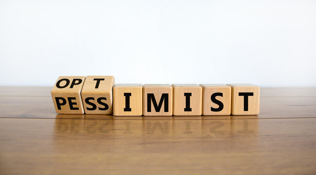 Pessimist or optimist symbol. Turned cubes and changed the word 'pessimist' to 'optimist'. Beautiful wooden table, white background. Business and optimist or pessimist concept. Copy space.