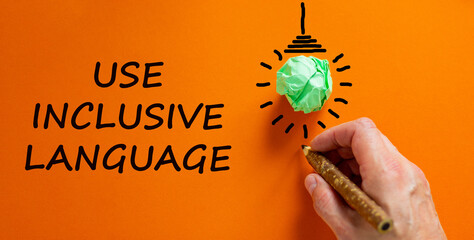Use inclusive language symbol. Businessman writing words 'Use inclusive language', isolated on orange background. Light bulb icon. Business and use inclusive language concept. Copy space. © Dzmitry
