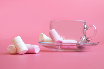 empty transparent cup on pink background with marshmallows
