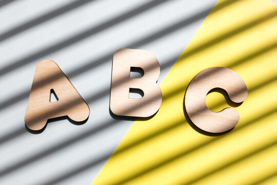 Wooden letters ABC on blue and yellow background. The concept of the importance of education. Background with diagonal shadows.