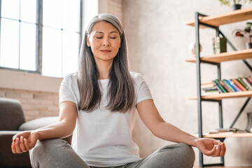 Relaxed mature caucasian woman meditating at home