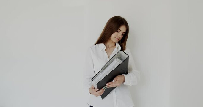 Confident girl with black folder in hands smiles at camera on white background