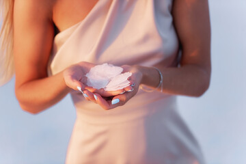 Close-up portrait of a young blonde woman holding a piece of crystallized white salt in her hands....