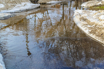 Slush.Huge children's puddle on the playground.Asphalt road covered with melting dirty snow and mud.Spring thaw