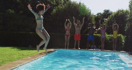 Diverse group of friends having fun jumping into a swimming pool