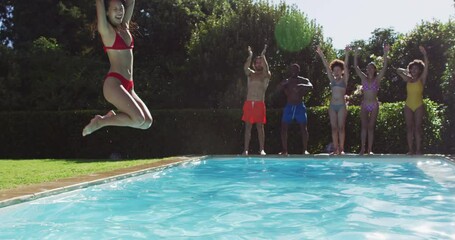 Diverse group of friends having fun jumping into a swimming pool