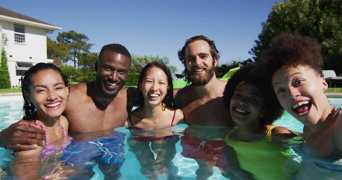 Diverse group of friends having fun taking a selfie in swimming pool