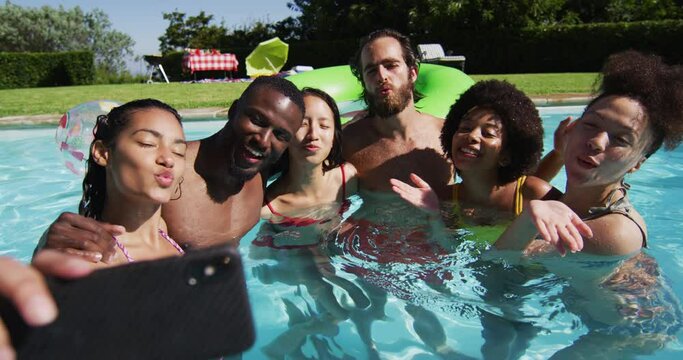 Diverse group of friends having fun taking a selfie in swimming pool