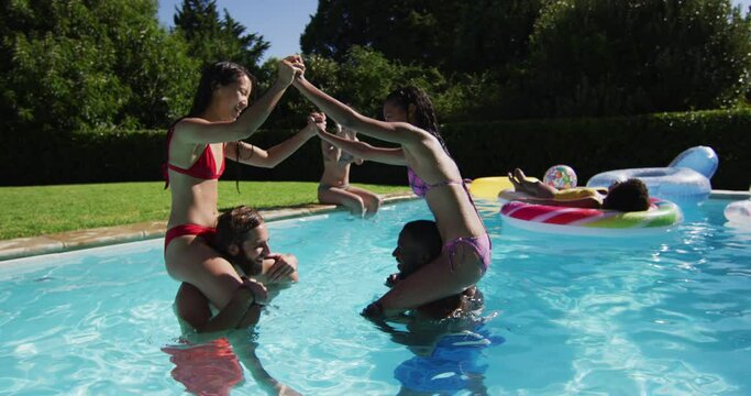 Diverse group of friends having fun playing in swimming pool
