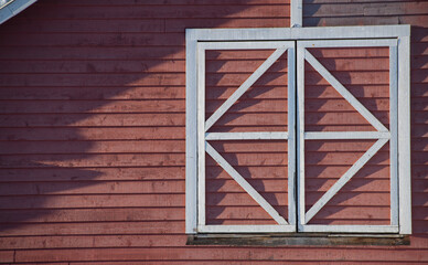 white traditional window frame on red wooden shingled barn framed with geometric shapes of...