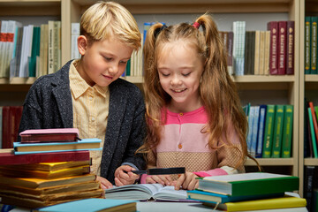 boy and girl kids reading books in library, people lifestyles and education concept. Young...