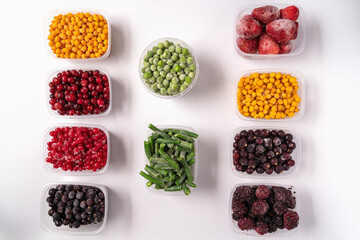 Frozen berries and vegetables in plastic boxes isolated on white background.