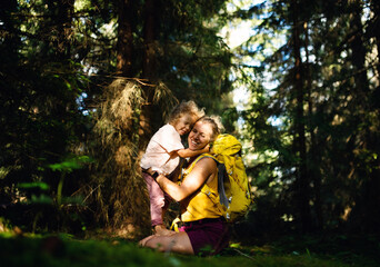 Happy mother with small daughter outdoors in summer nature, hugging and resting.
