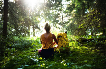 Naklejka na ściany i meble Rear view of woman hiker sitting on the ground outdoors in forest, resting.