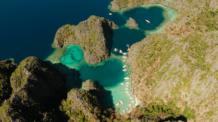 Aerial view tourist boats in lagoons. Kayangan Lake. lagoons, mountains covered with forests.coves with blue water among the rocks. Seascape, tropical landscape. Palawan, Philippines