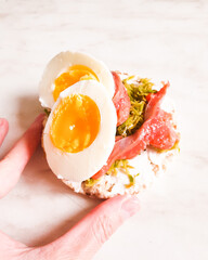 Simple open sandwiches on bread with egg and salmon with hand. The concept of healthy eating.