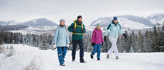 Family with small daughters on a walk outdoors in winter nature, Tatra mountains Slovakia.