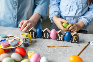 Fototapeta na wymiar Mom and daughter paint eggs with colors. Have fun. Happy family is preparing for Easter.