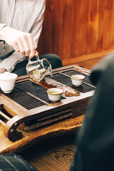Chinese tea ceremony, a man pours tea into cups on a bamboo table chaban