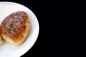 Close up Turkish pastry pogaca on black background with copy space. Pastry food in white plate, breakfast snack.
