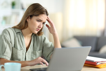 Frustrated student reading content on laptop at home