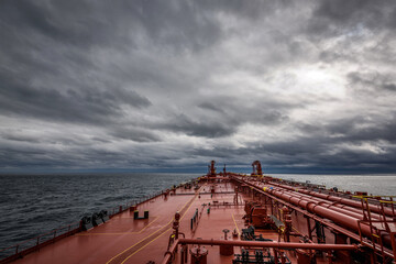 A super tanker is proceeding by ocean with overcast sky