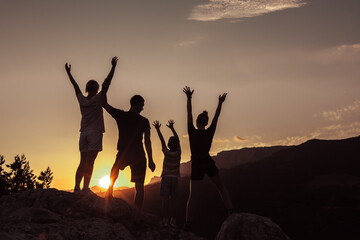 Joyful family of two parents, daughter and young son, raising arms up together. Concept of success,...