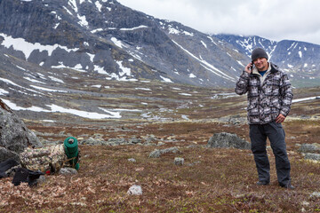 Backpack traveler calls with mobile phone with weak signal, speaks with smartphone