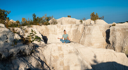 Young woman doing yoga exercises outdoor in the white mountains. Relax yoga at the top of the...