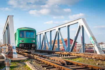 structure of gray metal railway bridge with a green train. Old railway bridge over the water