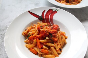 plate with penne pasta with tomato sauce and chopped carrots, Italian dish with tomato sauce, hot pasta seasoned with sauce