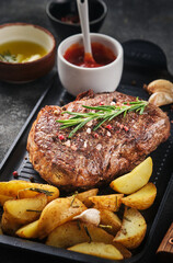 Juisy new york strip steak with rosemary, garlic and potato on skillet pan.