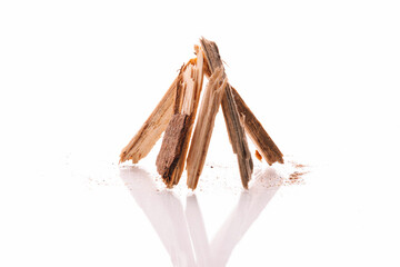 Small pile of wood chips in view of hut of branches fire constructed by crossing wood touching each other at the top on white background. Biofuel heating concept with reflection