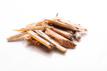 Small pile of wood chips in view of fallen hut of branches fire constructed by folded on two different sides wood on white background. Biofuel heating concept with reflection