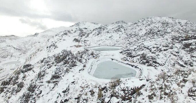 Beautiful aerial view of mountains covered by snow in foggy weather after a snowstorm. Cloudy weather and mountains covered with thick layer of snow. Frozen trees and lakes. Holiday vacations