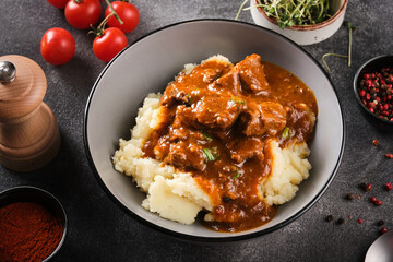 Beef stew in tomato sauce with mashed potatoes. Goulash with sauce and potatoes.