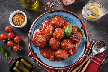 Meatballs in tomato sauce. Homemade swedish meatballs with  tomato sauce in blue plate over grey background. Top view, flat lay, close up.
