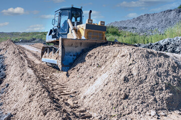 the process of leveling sand with a modern bulldozer during the construction of a dirt road
