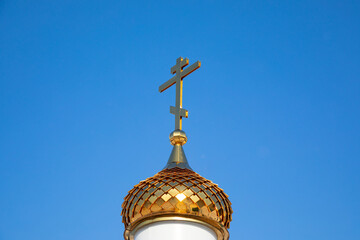 Fototapeta na wymiar Golden cross and dome of the Orthodox Church against the blue sky.